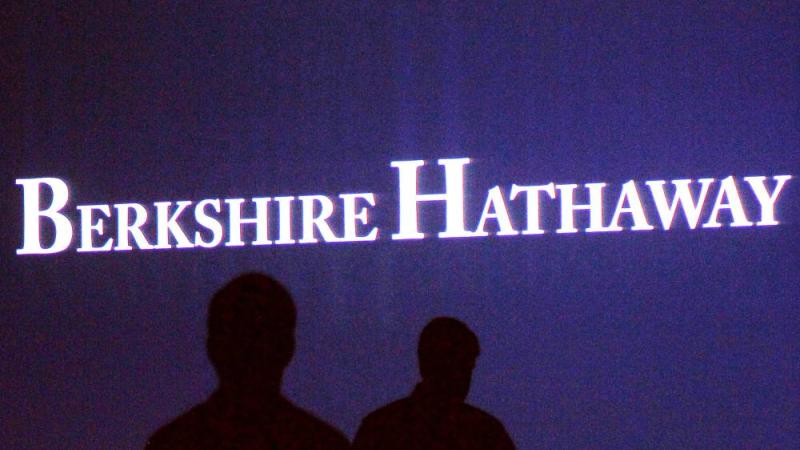 مساهمو «بيركشاير هاثاواي» يسيرون أمام شاشة بالاجتماع السنوي للشركة في أوماها (رويترز)