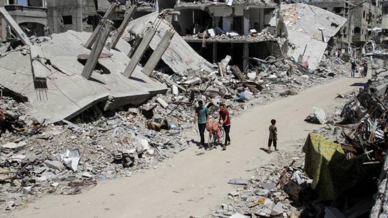 فلسطينيون يسيرون بين أنقاض المباني المتضررة في رفح