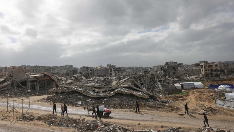 فلسطينيون ييرون على الطرق المحاذية للمباني المدمرة في جباليا (أ ف ب)