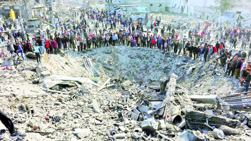 فلسطينيون يتجمعون حول حفرة كبيرة أحدثتها غارة إسرائيلية على حي الزيتون في غزة