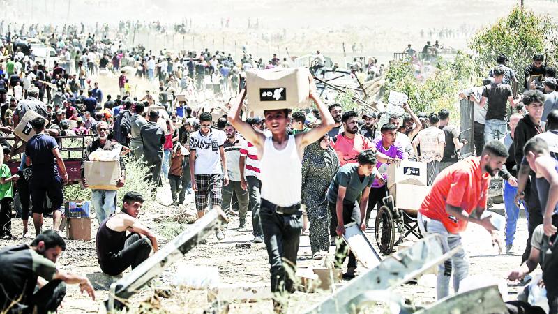 فلسطينيون يحملون صناديق مساعدات من مركز توزيع وسط قطاع غزة 