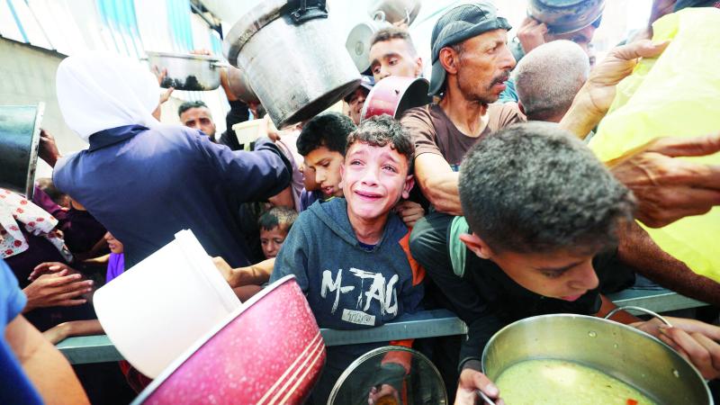 طفل يبكي وسط حشد ينتظر الطعام عند نقطة توزيع في النصيرات 