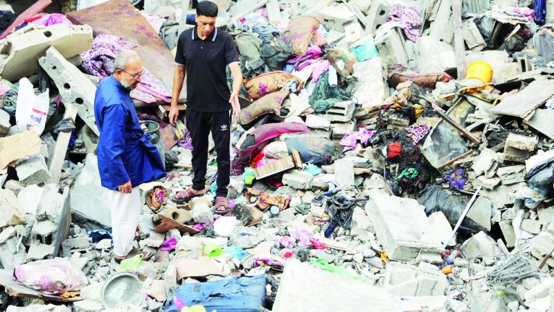 فلسطينيان يتفقدان الأضرار بعد غارة إسرائيلية على مخيم الشاطئ في غزة 