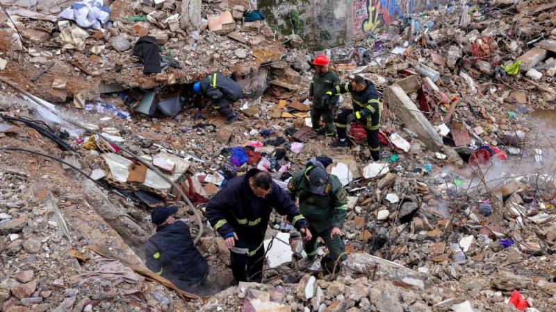 فرق الدفاع المدني والإنقاذ اللبنانية بين أنقاض المبنى السكني المنهار في طرابلس (أ ف ب)