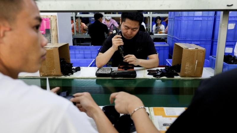 موظفون في خط تجميع حوامل الهواتف الذكية للسيارات في مصنع لملحقات البلاستيك، في دونغقوان، بمقاطعة قوانغدونغ، الصين (رويترز)