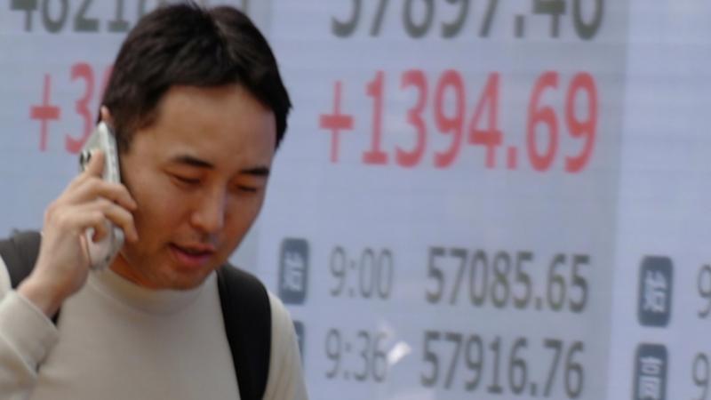 أحد المارة أمام شاشة لمؤشر الأسهم اليابانية