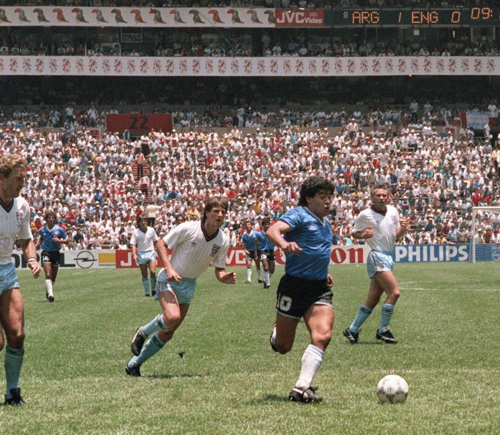 Argentinian forward Diego Armando Maradona runs past English defenders Terry Butcher (L) and Terry Fenwick (2nd L) on his way to scoring his second goal during the World Cup quarterfinal soccer match between Argentina and England 22 June 1986 in Mexico City. Argentina advanced to the semifinals with a 2-1 victory. AFP PHOTO (Photo by STAFF / AFP)