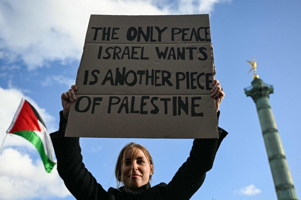 تحمل لافتة كتب عليها "إسرائيل تريد قطعة إضافية من فلسطين" خلال تظاهرة في روما 4 أكتوبر 2025 (أ.ف.ب)