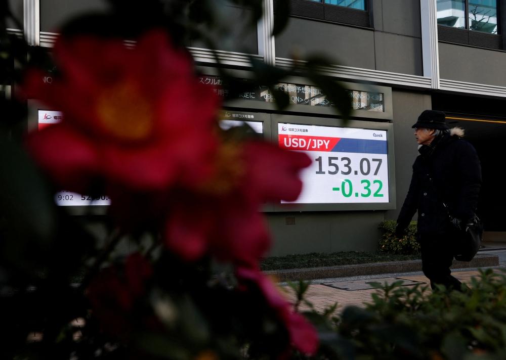 أحد المارة يطالع تحركات الأسهم والين على شاشة أحد البنوك في طوكيو