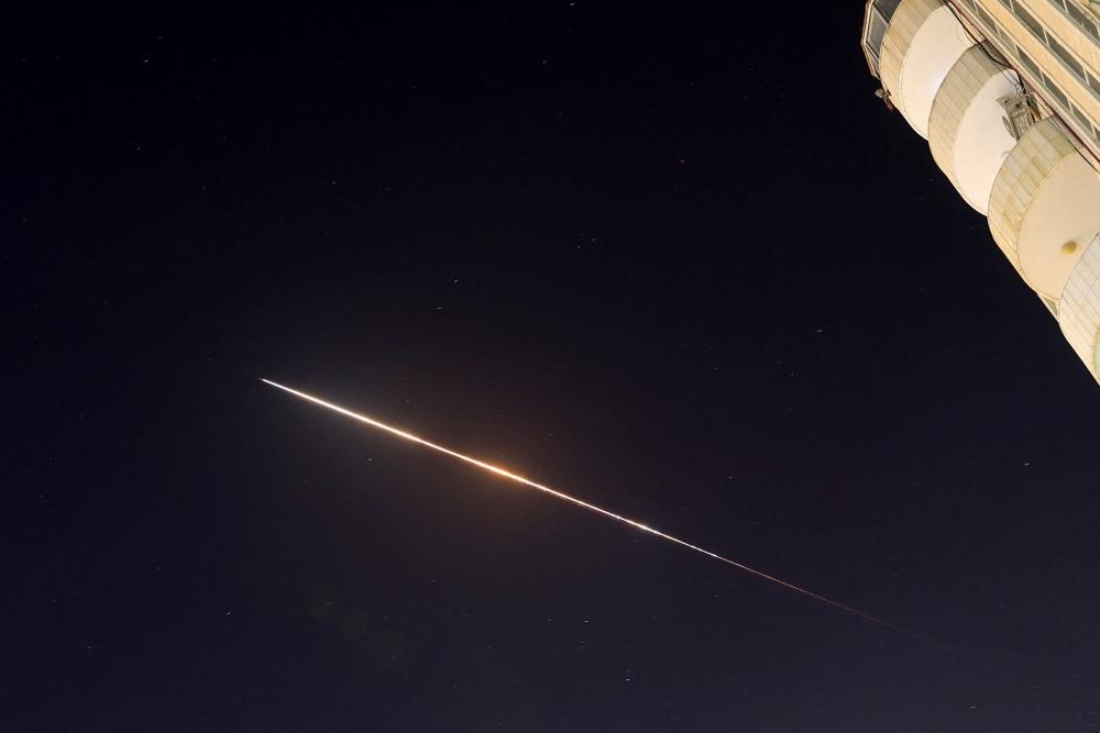 صاروخ إيراني يتجه نحو إسرائيل كما يبدو فوق مدينة الخليل الفلسطينية في الضفة الغربية المحتلة (رويترز)