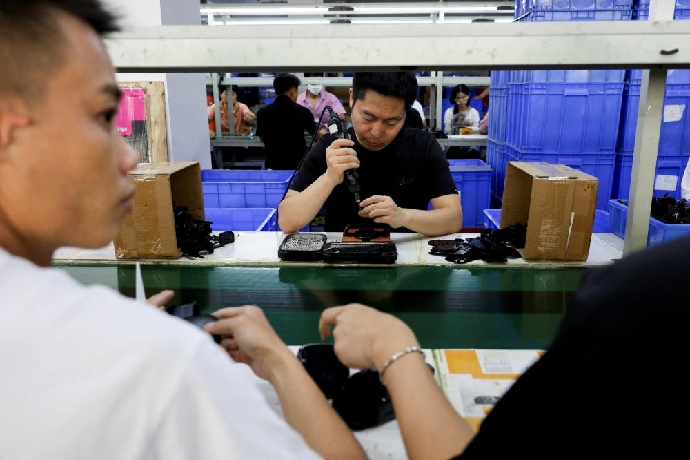 موظفون في خط تجميع حوامل الهواتف الذكية للسيارات في مصنع لملحقات البلاستيك، في دونغقوان، بمقاطعة قوانغدونغ، الصين (رويترز)