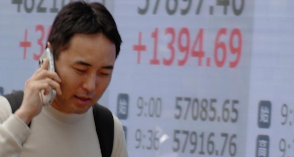 أحد المارة أمام شاشة لمؤشر الأسهم اليابانية