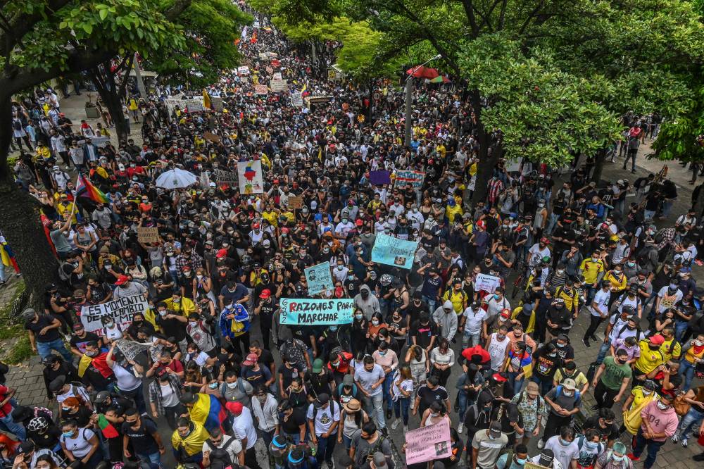 People protest against a tax reform billcthey say will leave them poorer as the country battles its deadliest phase yet of the coronavirus pandemic, in Medellin, Colombia, on May 1, 2021. - Colombian President Ivan Duque caved in on April 30 to widespread anger and said he would overhaul the proposed tax reform. Duque announced he was shelving clauses that would lower the income tax threshold to broaden the tax base and raise value-added taxes on goods and services. (Photo by JOAQUIN SARMIENTO / AFP)