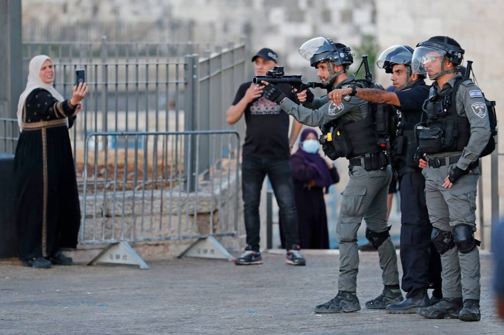  فلسطينية تلتقط صوراً لجنود إسرائيليين خلال تظاهرة رداً على «مسيرة الأعلام» في القدس القديمة (ا ف ب) 