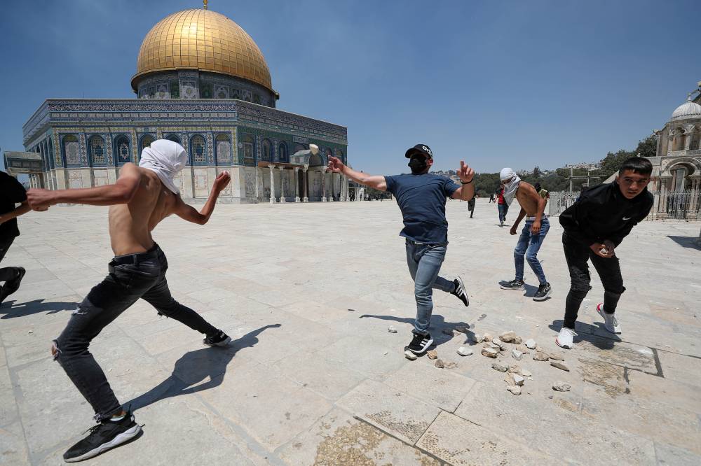 فلسطينيون يرشقون الحجارة في الأقصى وفي الإطار جندي إسرائيلي يطلق قنابل الغاز (رويترز، أ ف ب)