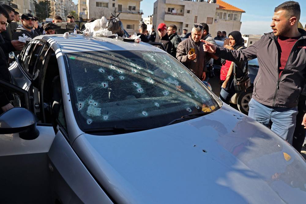 فلسطينيون يتفقدون السيارة التي قتل فيها الشبان الثلاثة في نابلس (ا ف ب) 