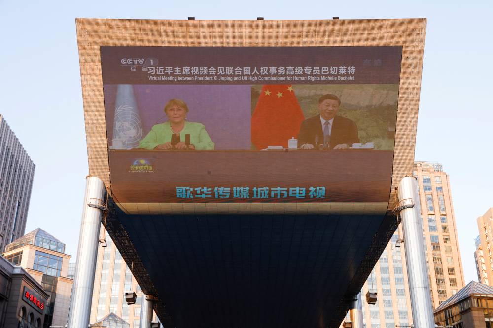 FILE PHOTO: Chinese President Xi Jinping and United Nations High Commissioner for Human Rights Michelle Bachelet are seen on a giant screen broadcasting news footage of their virtual meeting at a shopping complex in Beijing, China May 25, 2022. REUTERS/Carlos Garcia Rawlins/File Photo