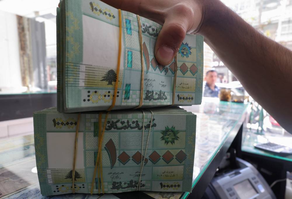 صرّاف يعرض عملات بالليرة اللبنانية في بيروت (رويترز) 