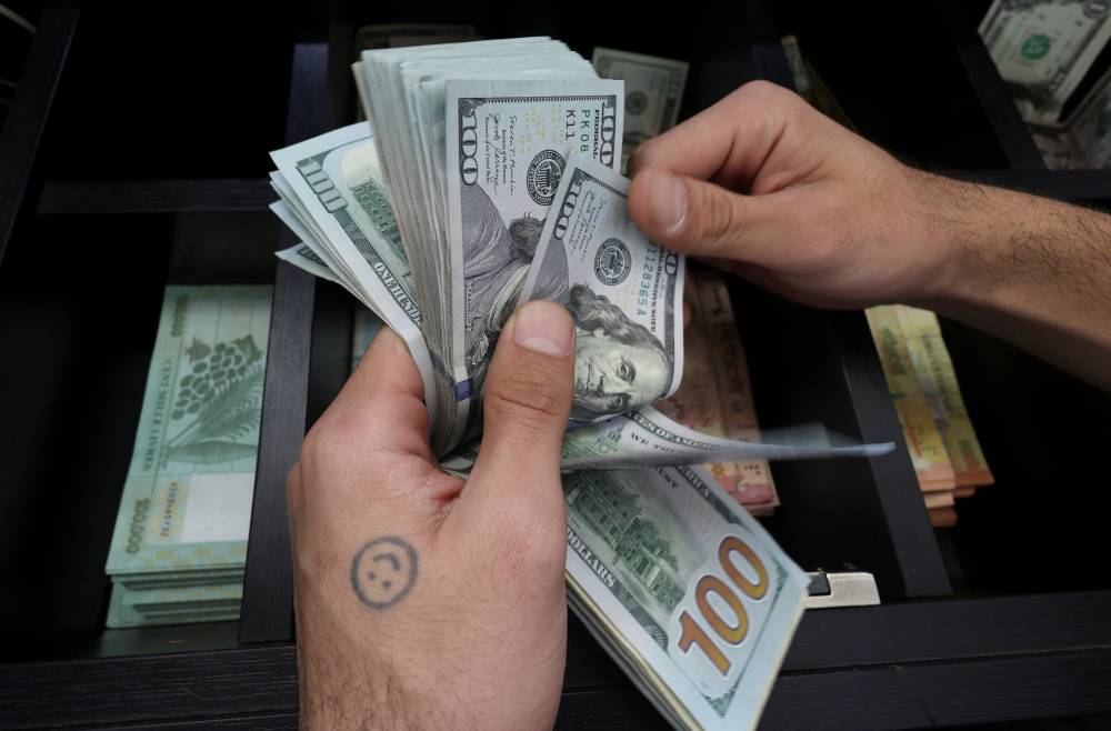 صرّاف يعد أوراقاً نقدية بالدولار الأمريكي في بيروت (رويترز)