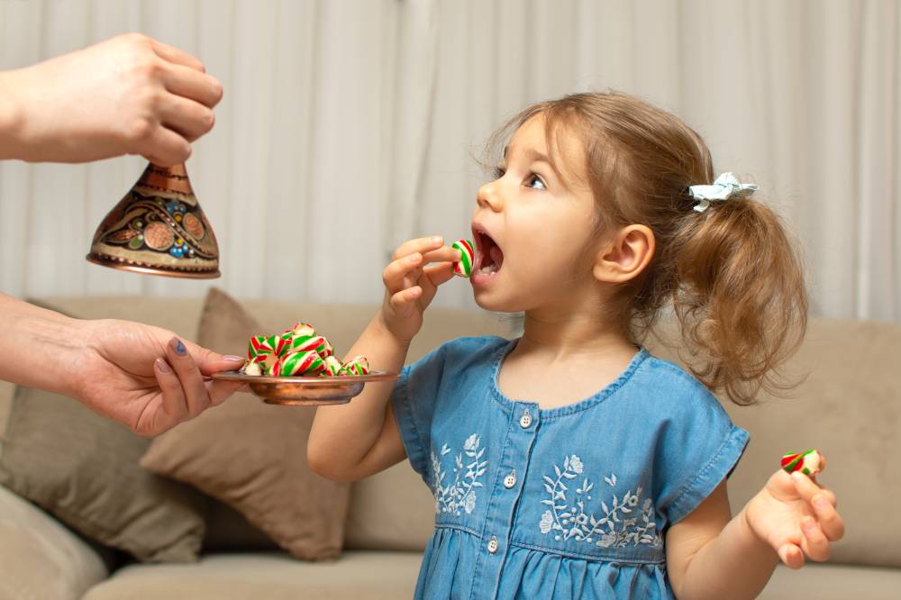 Child and traditional Ramadan candies. Colorful sweet and baby girl. Eid Mubarak. Kid hold plate full of sugar during Ramadan kareem (Turkish: Ramazan Bayrami).