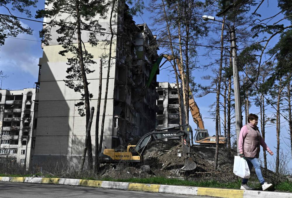  آلية ثقيلة تهدم مجمعاً سكنياً متضرراً من القصف في اربين ضاحية كييف (أ.ف.ب)