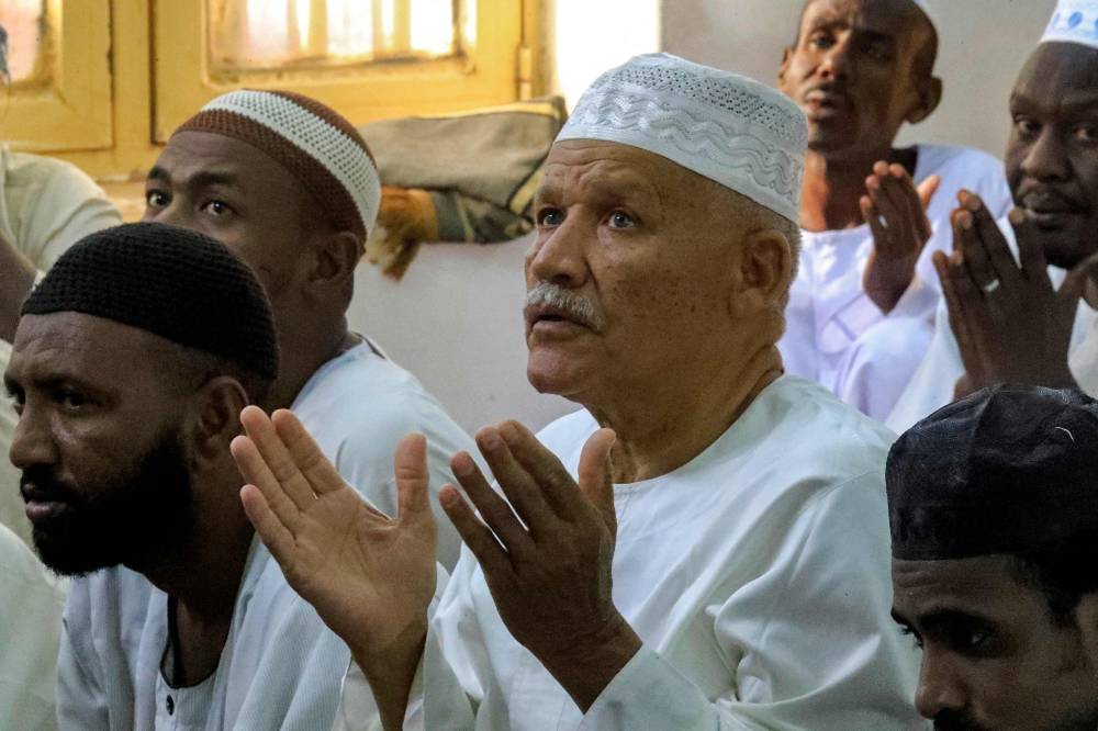 سودانيون يرفعون أيديهم بالدعاء خلال صلاة العيد في مسجد بمنطقة الجريف بالخرطوم (أ ف ب )