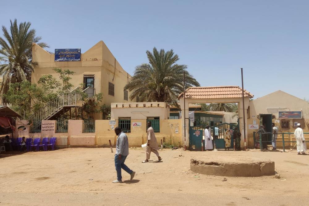 سودانيون يمشون خارج مستشفى البشير في جنوب الخرطوم مع تراجع القتال بالخرطوم ( اف ب)