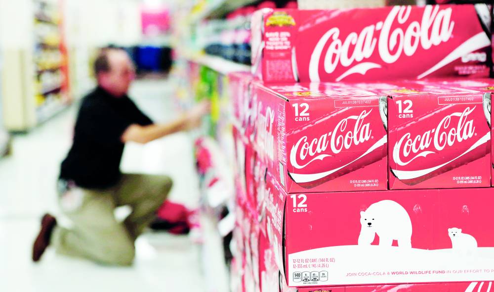 FILE PHOTO An employee arranges bottles of Coca-Cola at a store in Alexandria, Virginia October 16, 2012. REUTERS/Kevin Lamarque/File Photo