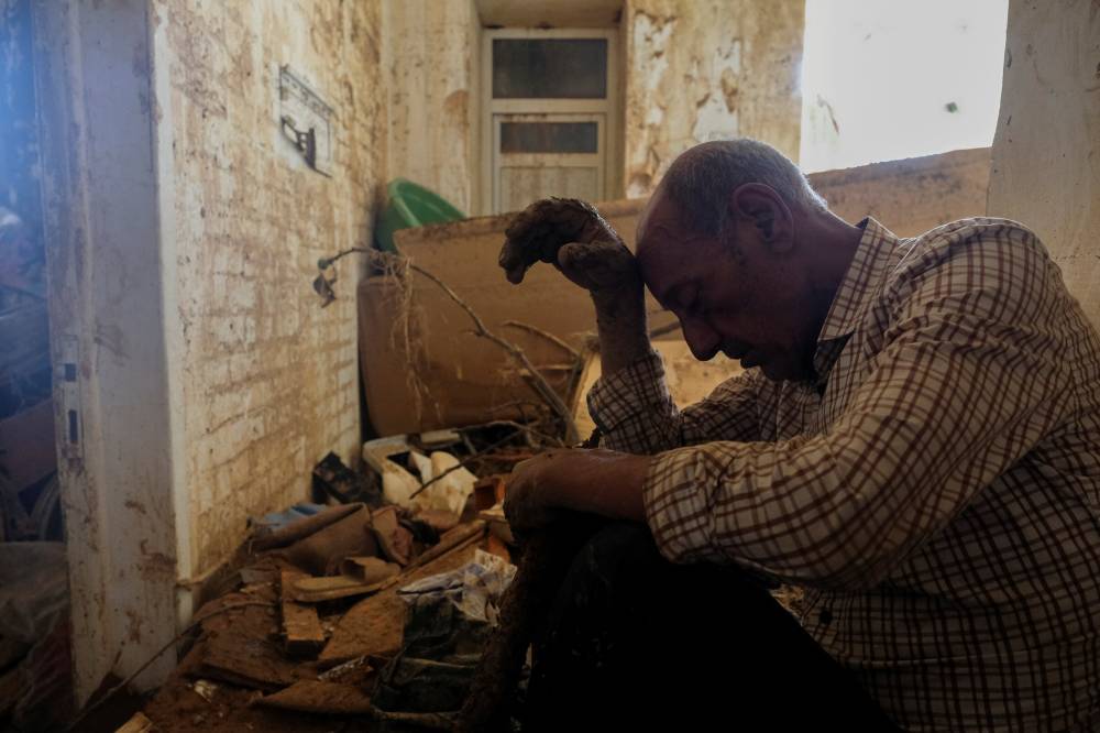 ليبي فقد بناته واثنين من أبنائه وحفيدته يجلس حزيناً خارج منزله المدمر في درنة(رويترز)