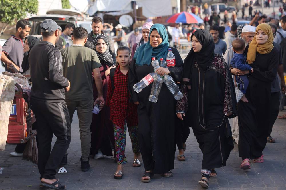 نساء فلسطينيات يحملن حاويات لجمع المياه الصالحة للشرب بخان يونس