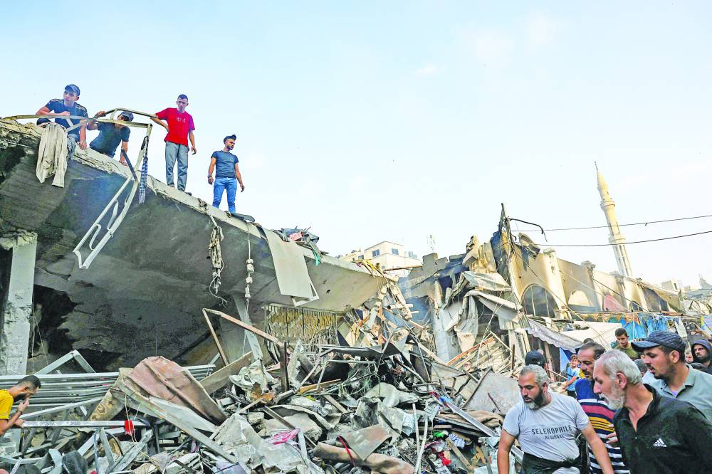  أشخاص وسط الدمار إثر الغارات الإسرائيلية على غزة (أ ف ب) 