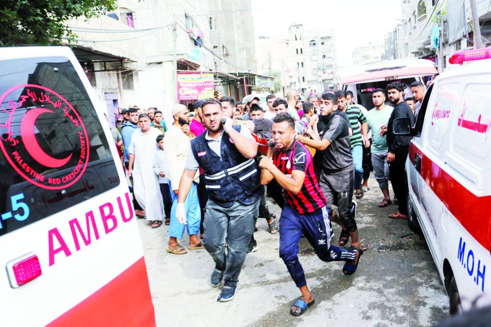 فلسطينيون يحملون جريحاً في موقع غارة إسرائيلية على منزل في رفح (رويترز)
