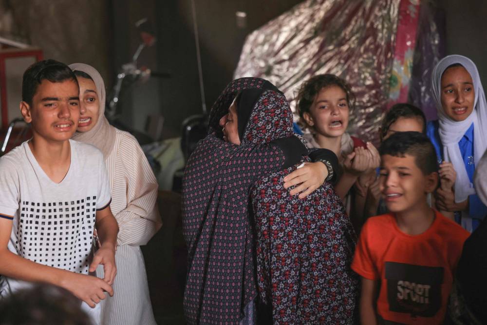 فلسطينيون يبكون خلال تشييع أفراد من عائلتهم الذين قُتلوا إثر غارة إسرائيلية على غزة
(أ ف ب)