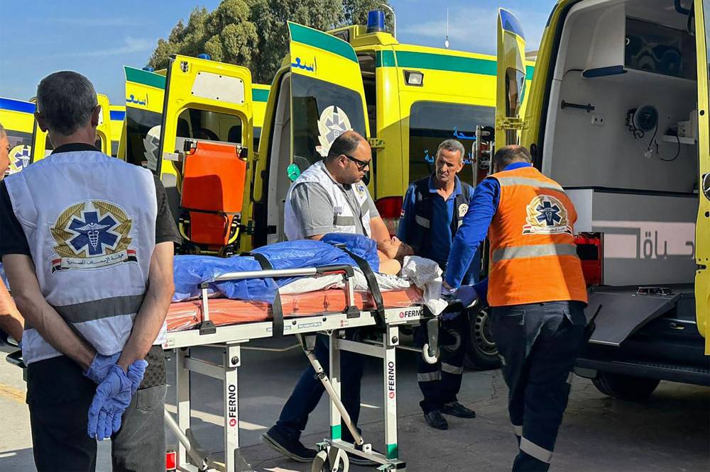 مسعفون ينقلون جريحاً فلسطينياً إلى سيارة إسعاف على الجانب المصري من معبر رفح (أ ف ب)