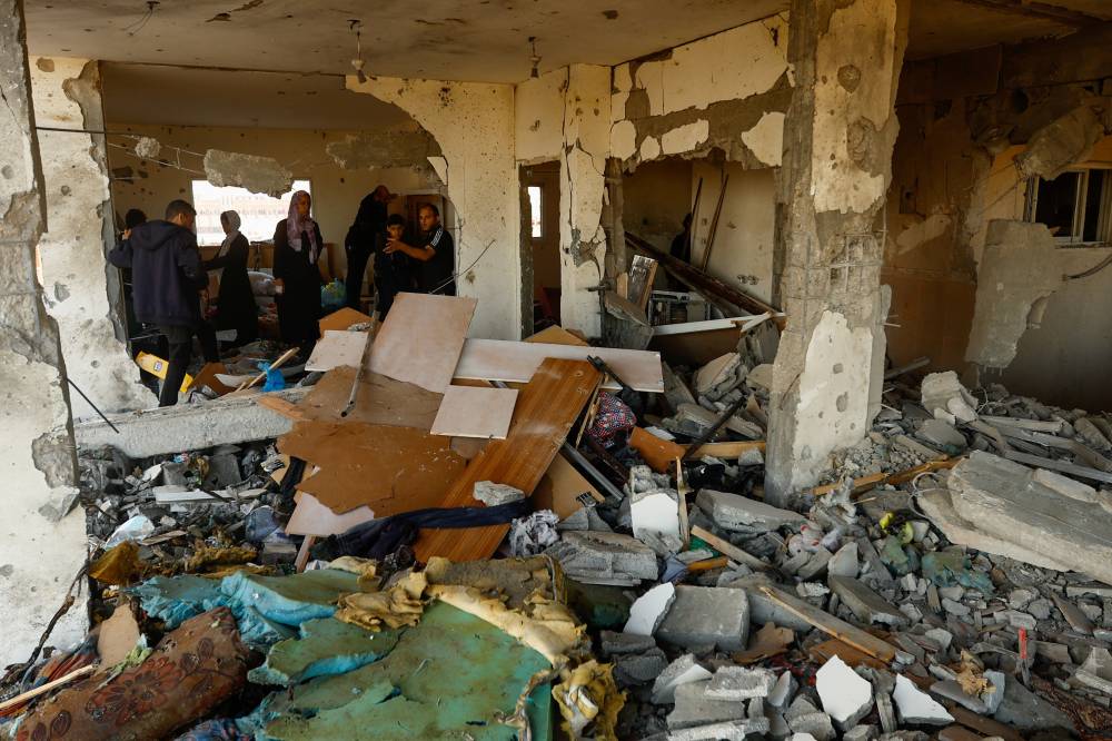عائلة تتفقد منزلها الذي قصف بغارة إسرائيلية على خان يونس (رويترز)