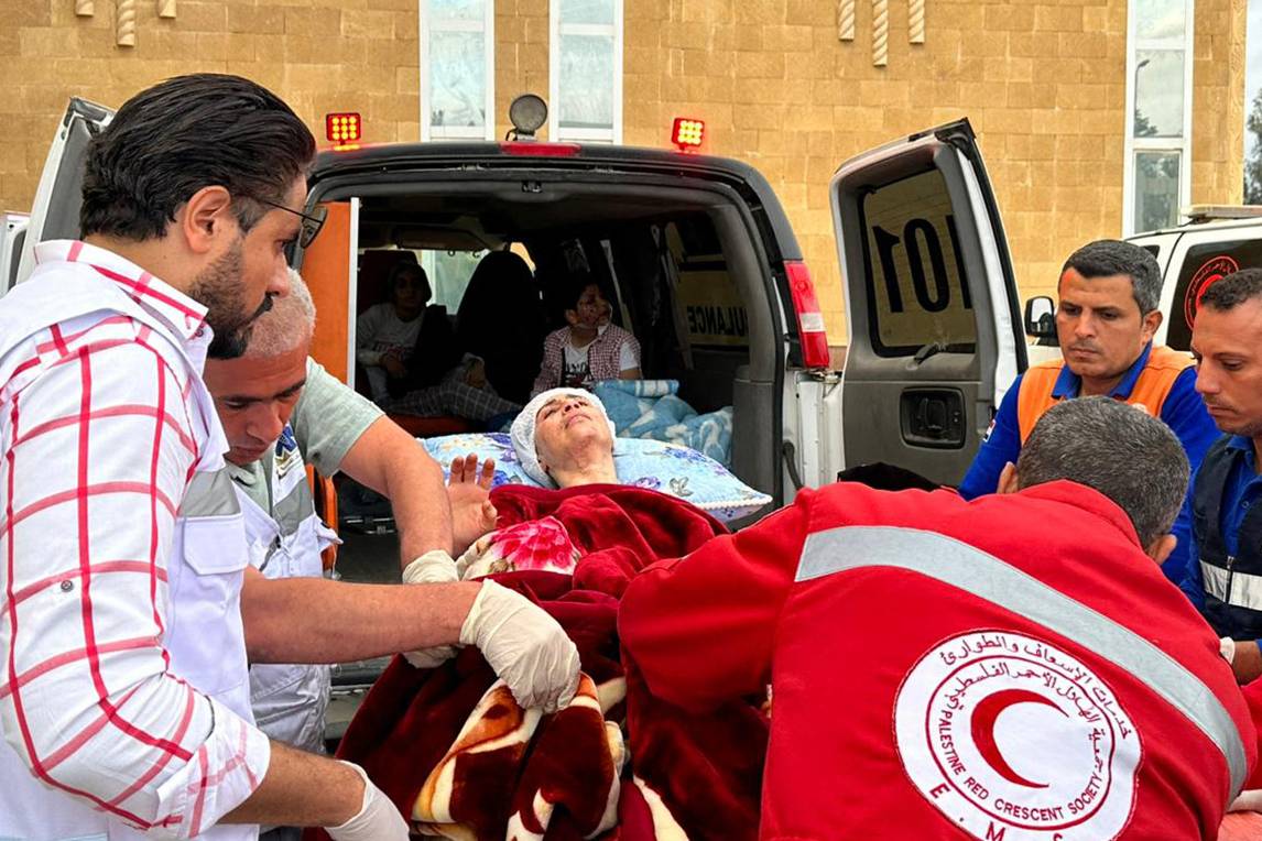 مسعفون ينقلون جريحا فلسطينيا عند وصوله من غزة إلى الجانب المصري من معبر رفح (أ ف ب) 