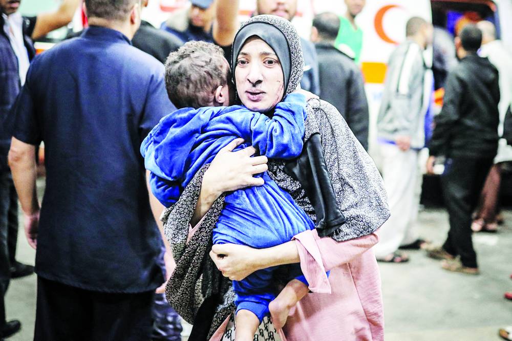 فلسطينية تندفع مع طفلها إلى المستشفى بعد القصف الإسرائيلي على خان يونس (أ ف ب)