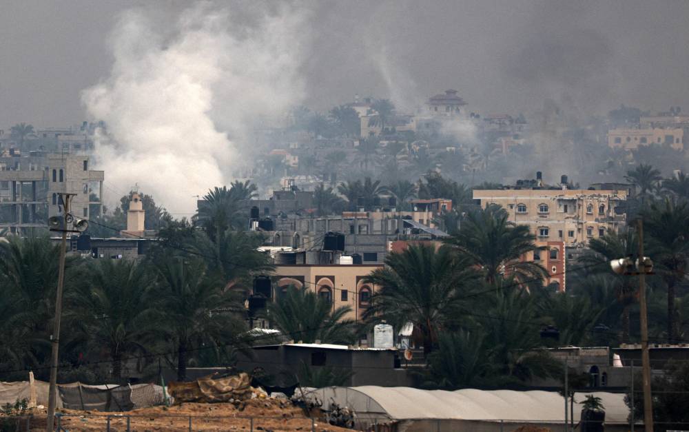 الدخان يتصاعد فوق المباني إثر القصف الإسرائيلي على خان يونس (أ ف ب)
