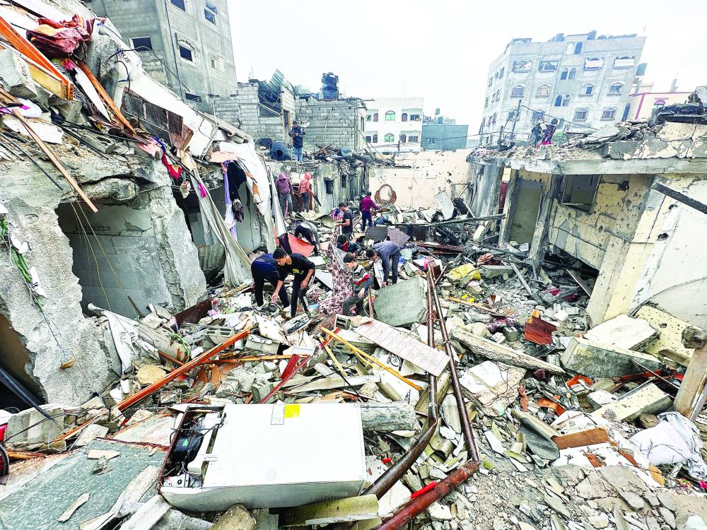 فلسطينيون يتفقدون موقع الغارات الإسرائيلية على رفح (رويترز) 