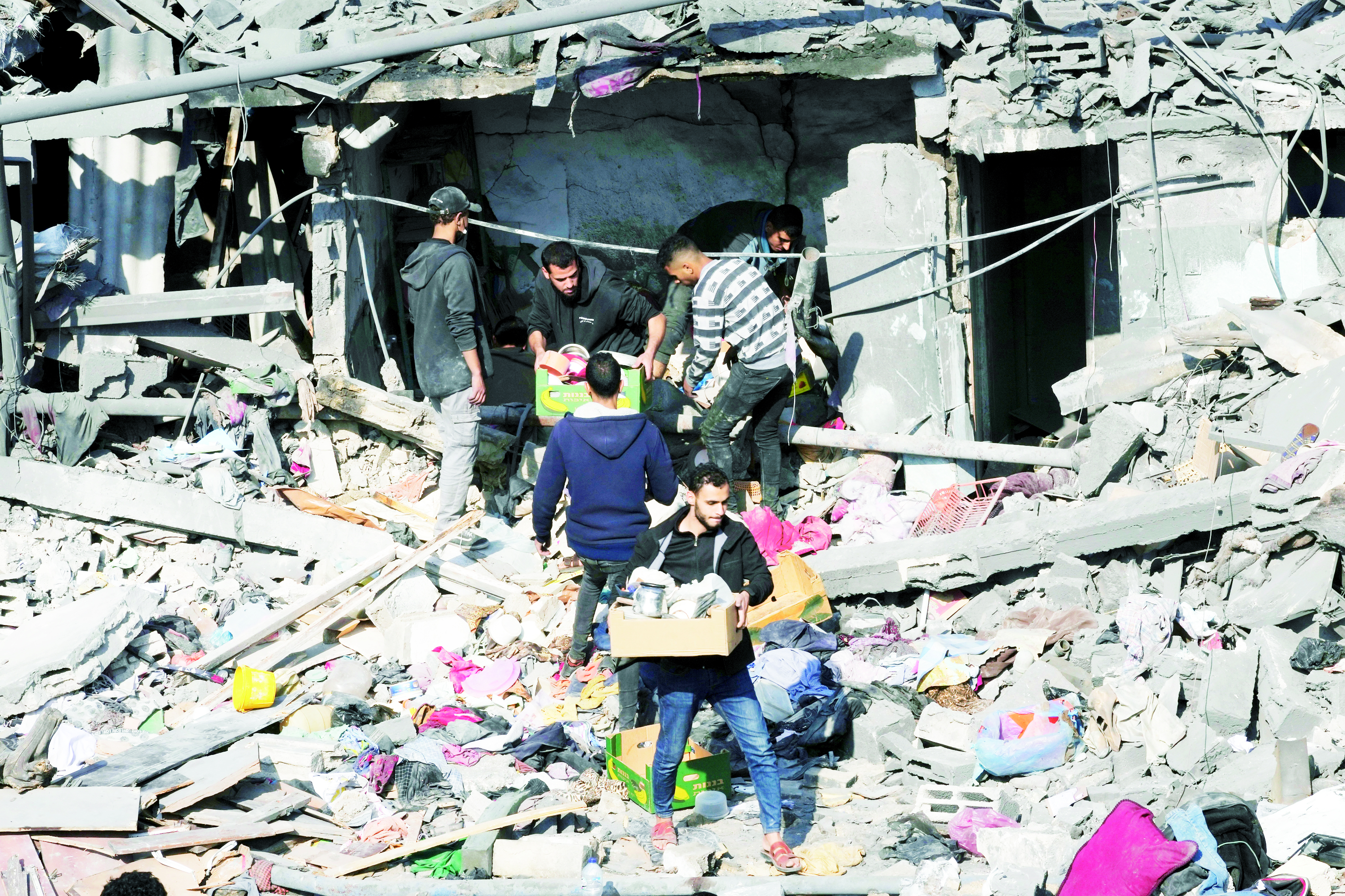  فلسطينيون يتفقدون مبنى مدمراً بعد غارة إسرائيلية على مخيم النصيرات (أ ب)