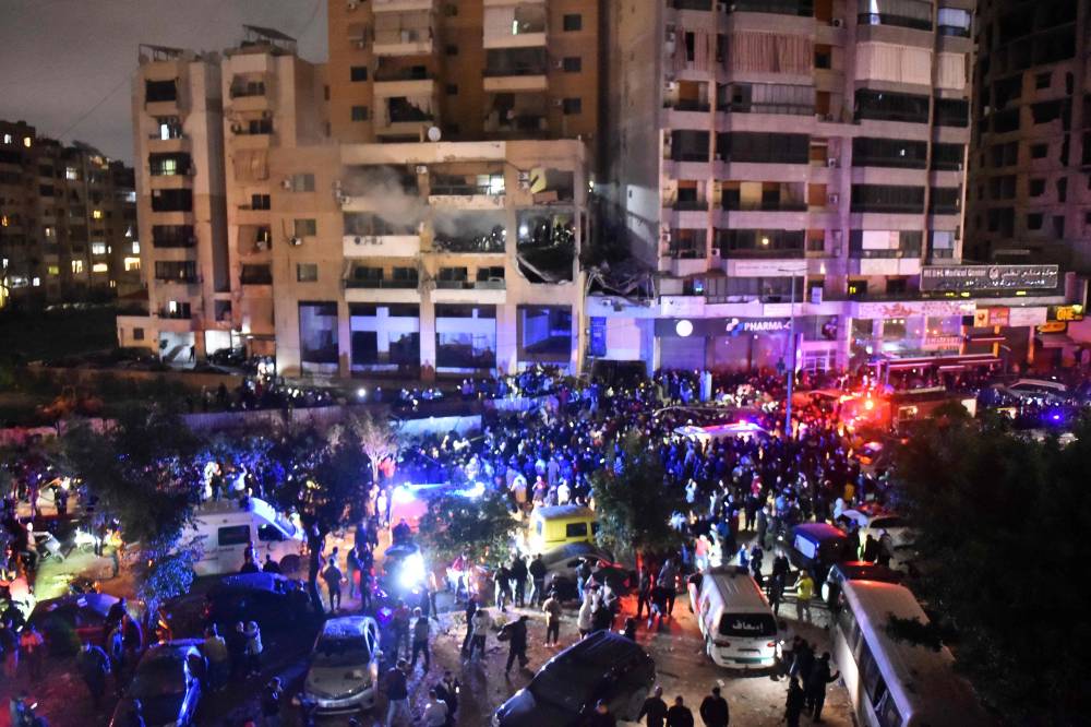  أشخاص يتجمعون في مكان الغارة الإسرائيلية على الضاحية الجنوبية لبيروت (ا ف ب)