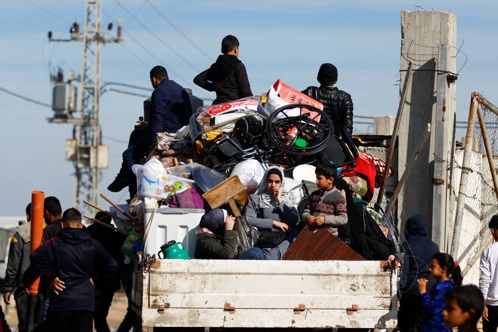 نازحون فلسطينيون يركبون شاحنة لدى وصولهم إلى رفح (رويترز) 