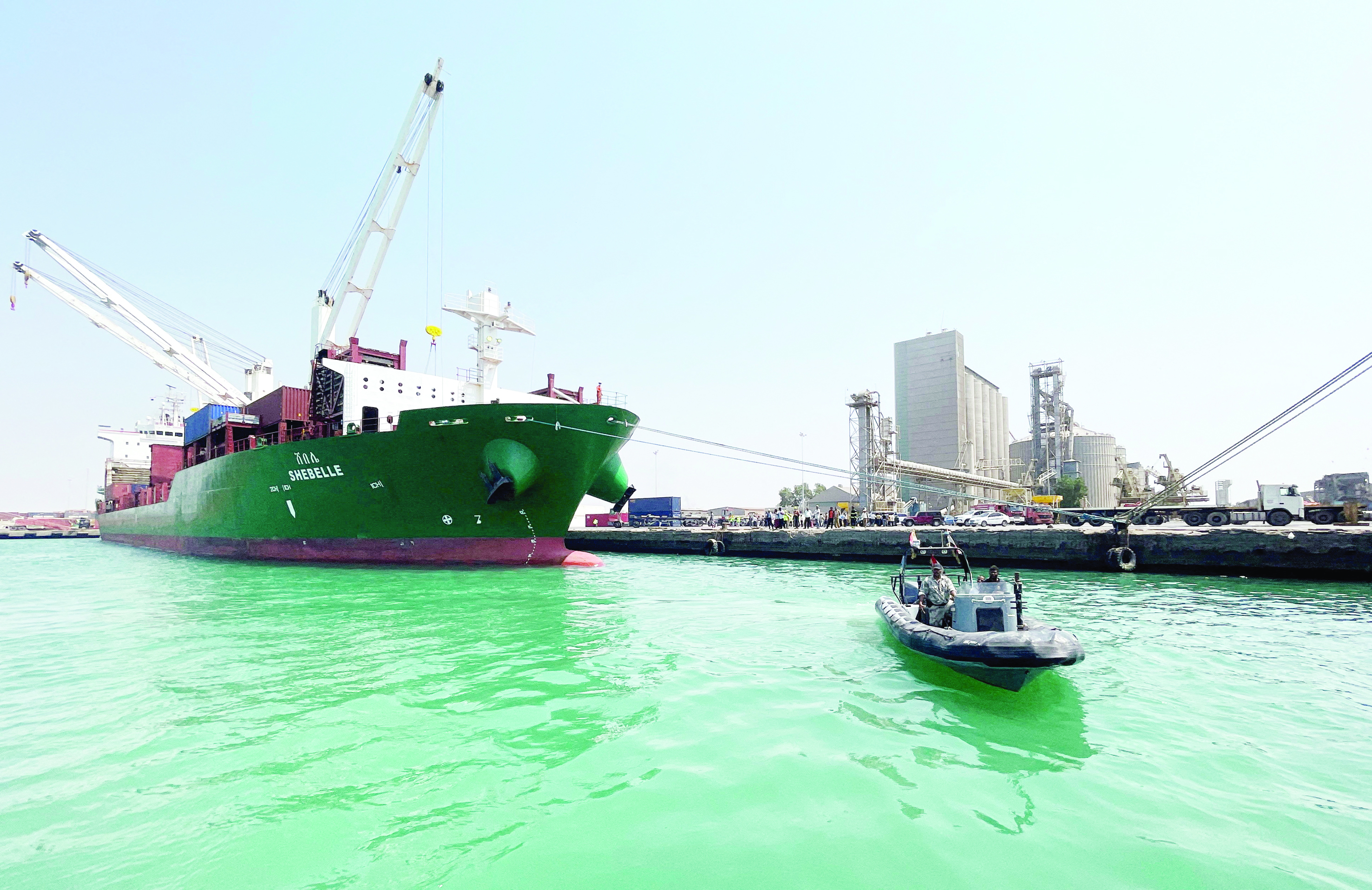  قارب لخفر السواحل يبحر أمام سفينة حاويات تجارية راسية في ميناء الحديدة على البحر الأحمر (رويترز) 