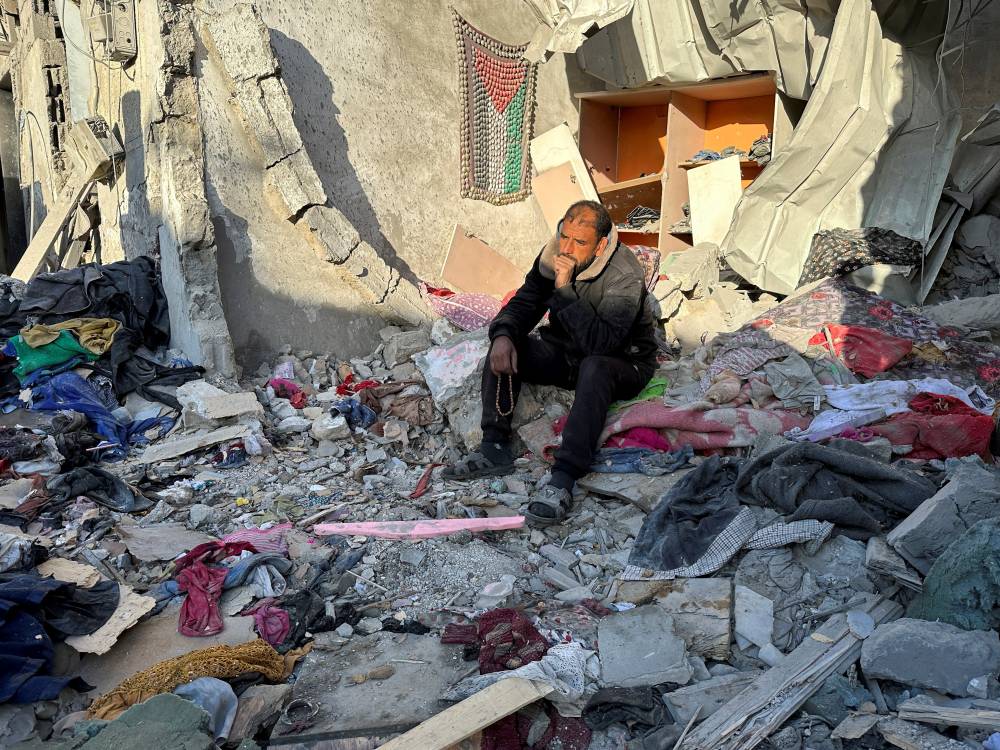 فلسطيني يجلس في منزله المدمر جراء غارة إسرائيلية على رفح (رويترز)