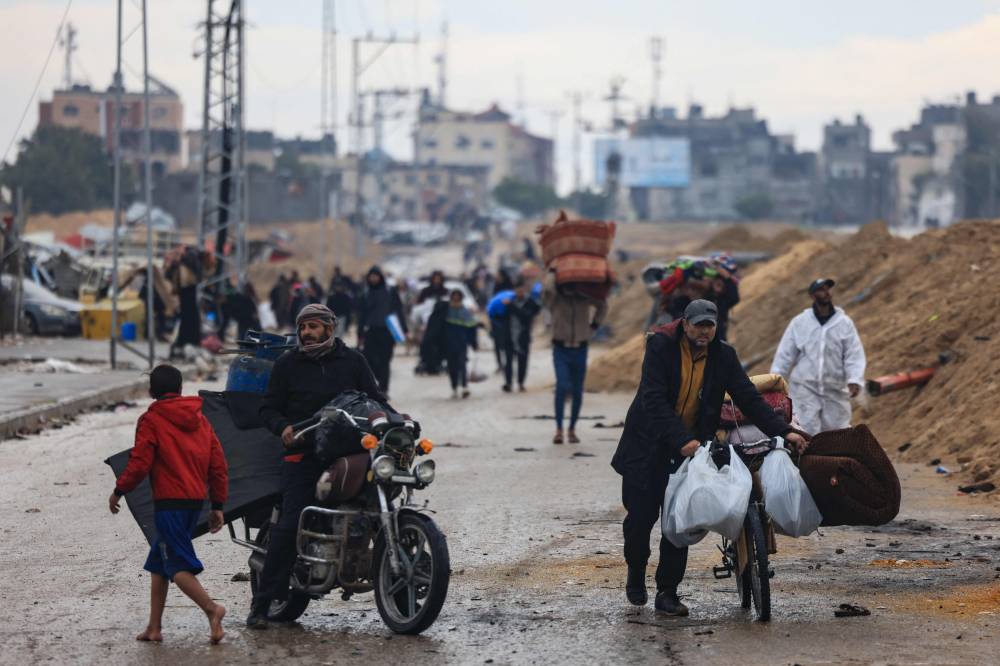 فلسطينيون يحملون بعض ممتلكاتهم وسط شارع في خان يونس (أ ف ب)
