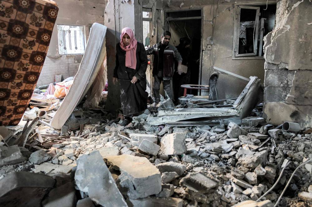 فلسطينيون يتفقدون شقة دمرت في القصف الإسرائيلي على رفح (أ ف ب)