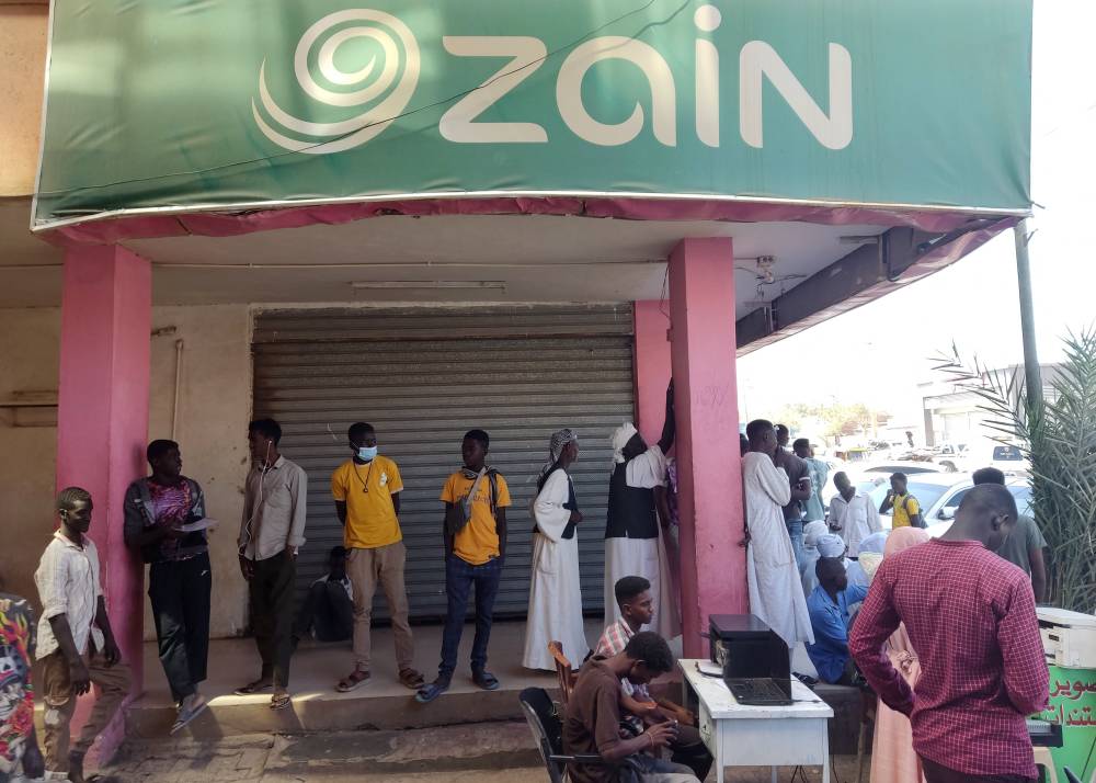 مدنيون سودانيون يصطفون خارج مكاتب شركة زين لخدمات الهاتف المحمول والبيانات في مدينة القضارف (اف ب)