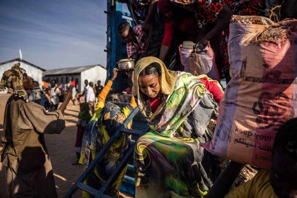 سيدة سودانية فرت من الحرب في السودان تنزل من شاحنة محملة بعائلات سودانية تصل إلى مركز عبور للاجئين ( اف ب)