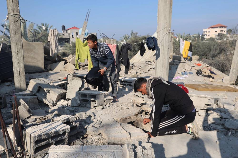  فلسطينيون يبحثون بين أنقاض منزلهم الذي دمرته غارة إسرائيلية شرق خان يونس (ا ف ب)