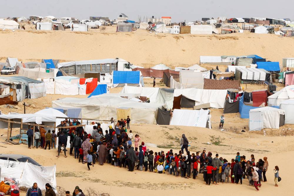 مهجرون ينتظرون الحصول على طعام مجاني في مخيم للنازحين برفح 